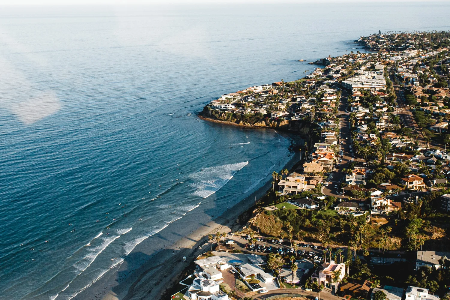 The San Diego coastline near Pacific Beach from the air, with waves rolling onto the sand below the homes