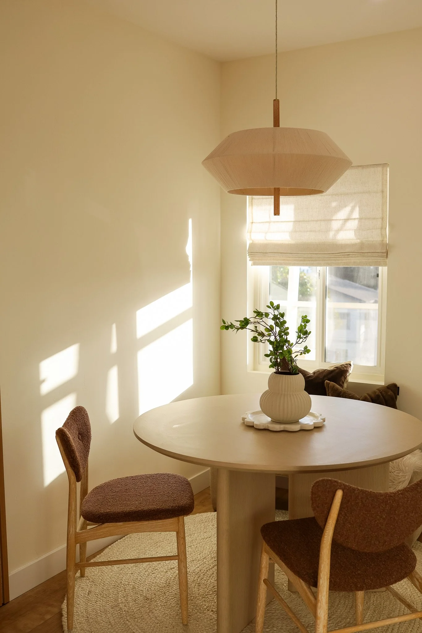 The sunlit dining nook in Unit Three at The Swell, with a round table and a paper pendant