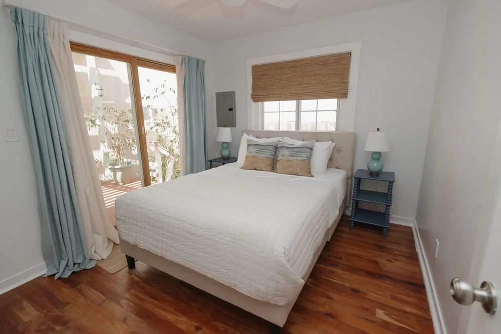 A bedroom in The Villa with wood floors, a sliding door and beach print pillows