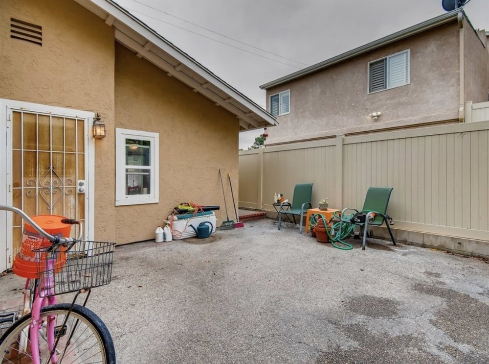Before: Backyard with a bare patio and stucco walls at OB Surfer's Paradise in Ocean Beach