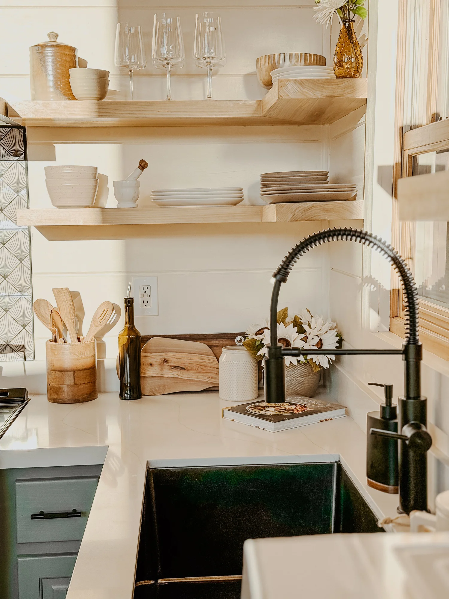 Kitchen sink with a black faucet, open wood shelves and white counters at Dark Moon Chalet in Julian, designed by Salt and Sky Lodging Co.