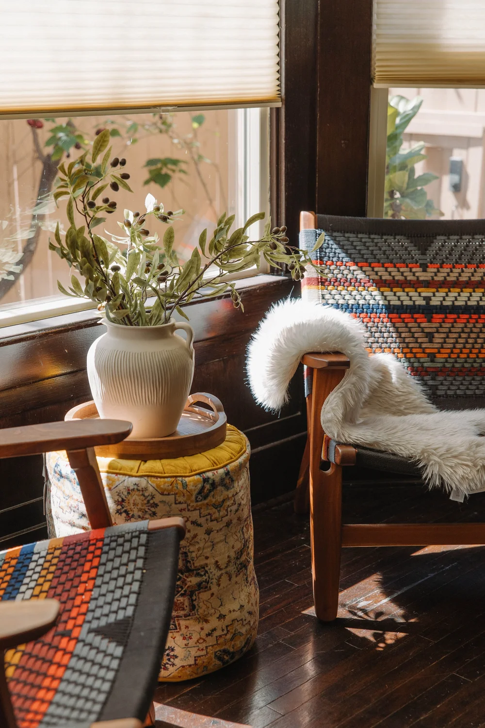 Woven chairs, a sheepskin throw and a vase of olive branches by the window in the living room at Palm Parkside