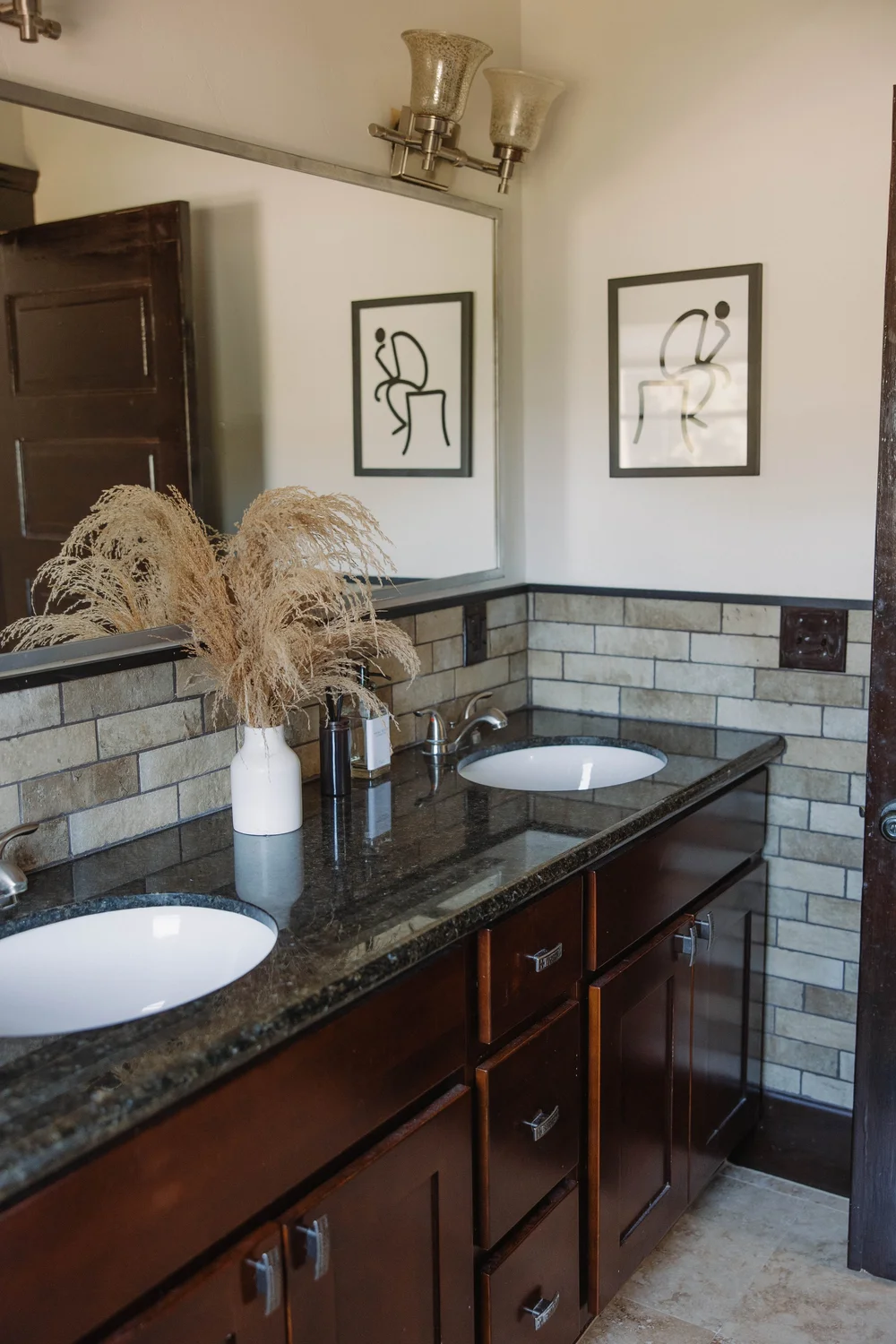 The double vanity in the master suite bathroom at Palm Parkside, with a granite counter and a brick backsplash