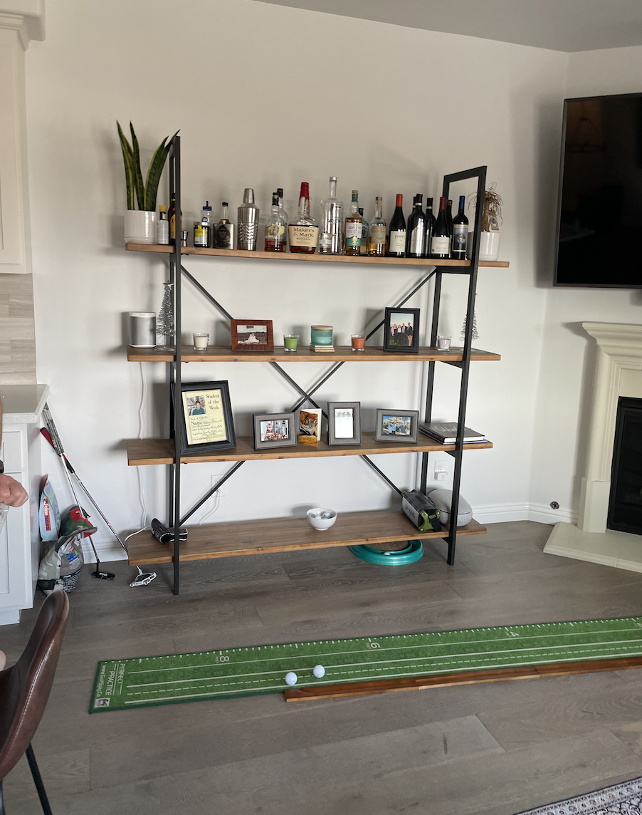 Before: Living room with metal shelving and a putting green at Coastal Palm in Pacific Beach