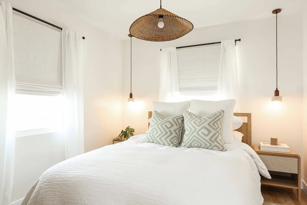The first bedroom with a woven pendant, sage patterned pillows and two hanging lights in Unit One at The Swell, Oceanside