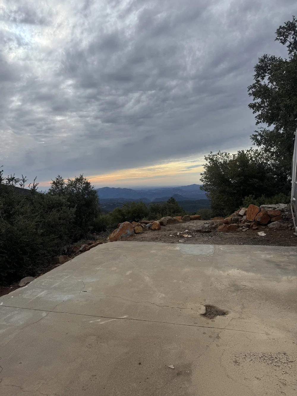 Before: the cracked concrete pad and rock piles facing the sunset view at Restore Outpost, Wild Moon Ranch, Julian