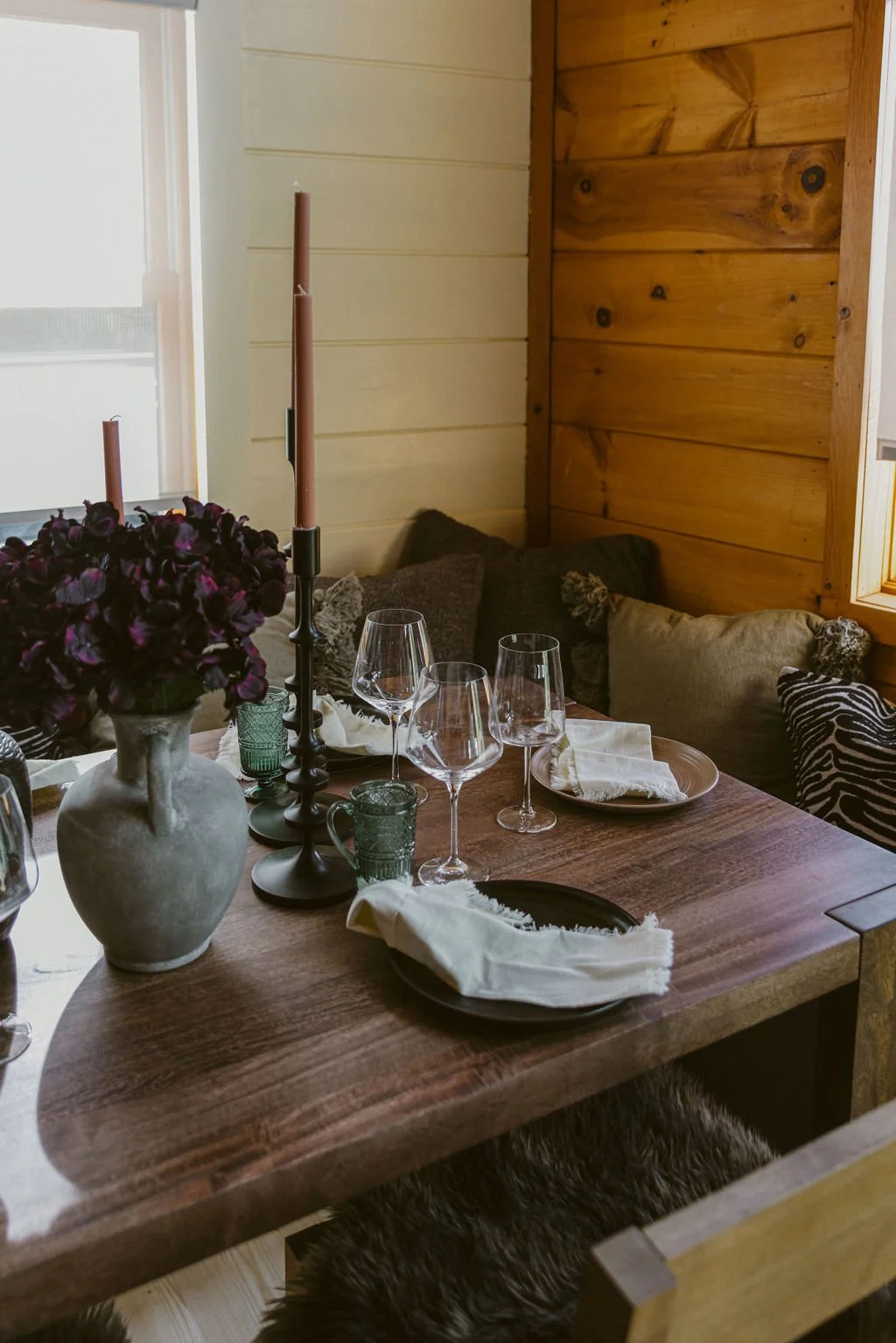 Dining table with candlesticks, wine glasses and dark flowers at Dark Moon Chalet in Julian, designed by Salt and Sky Lodging Co.
