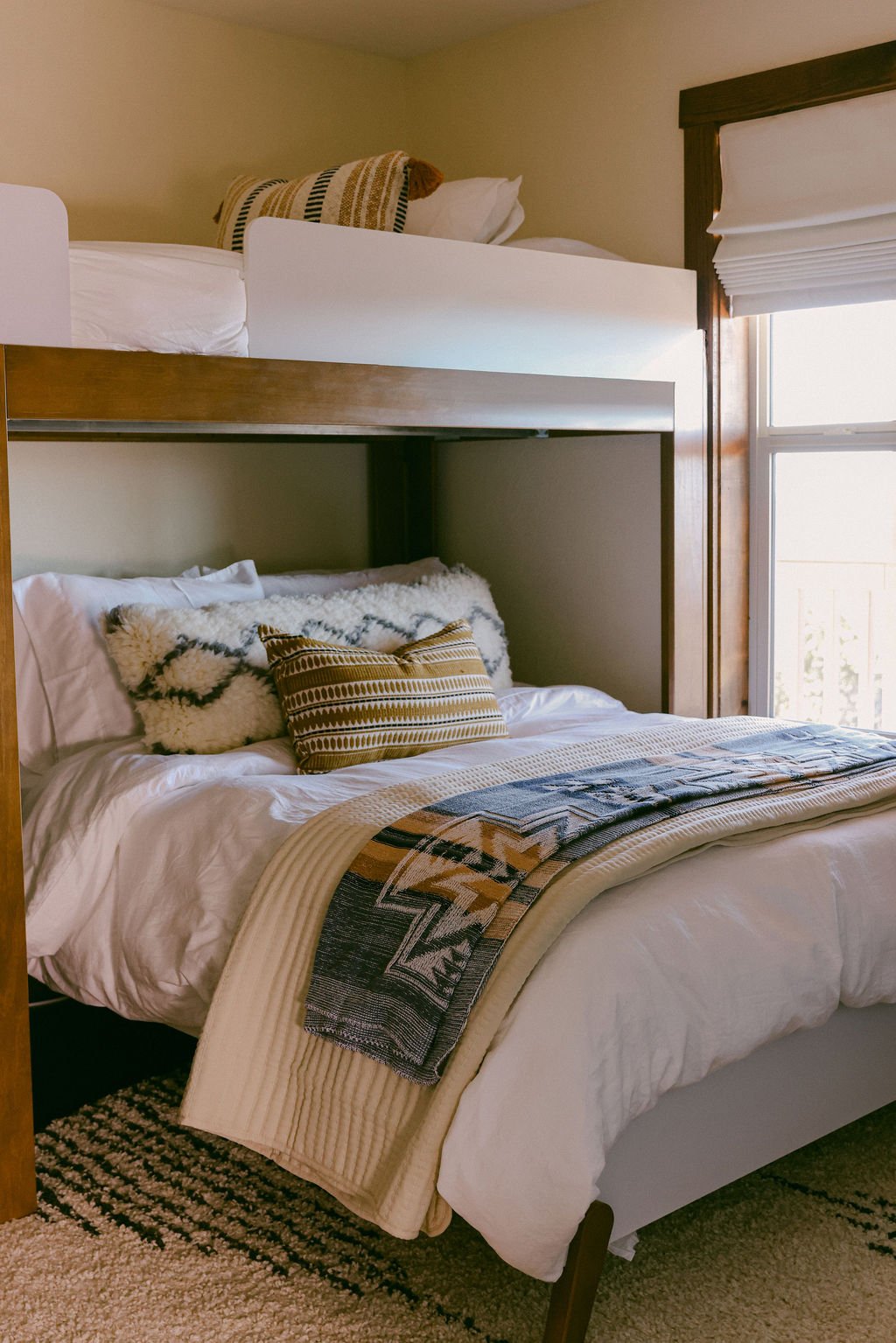 Bunk room with a woven blanket and western-print pillows