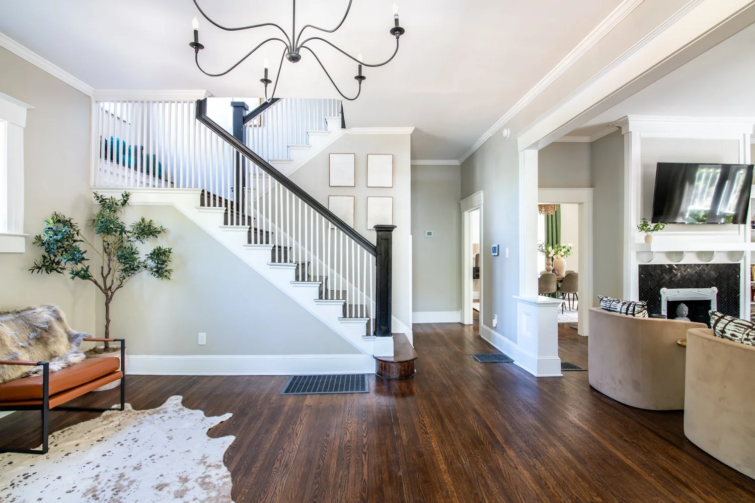 Entry hall with a staircase, chandelier and wood floors at Elmsgate in Birmingham, designed by Salt and Sky Lodging Co.