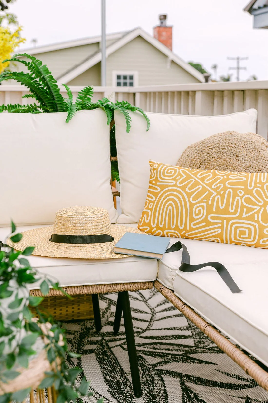 A straw hat and a book left on the cushions of a rattan patio sofa in the afternoon