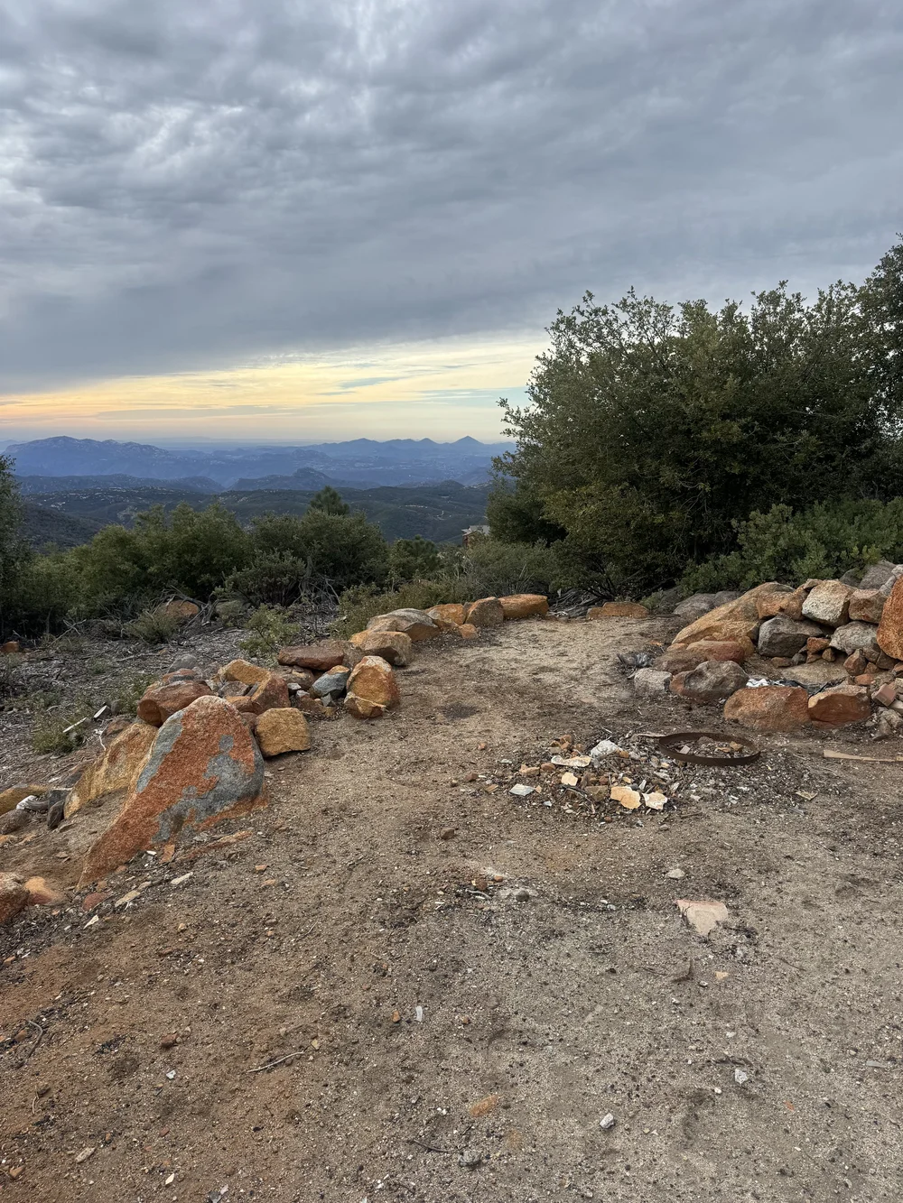 Before: a dirt clearing with loose rocks and an old fire ring at Restore Outpost, Wild Moon Ranch, Julian