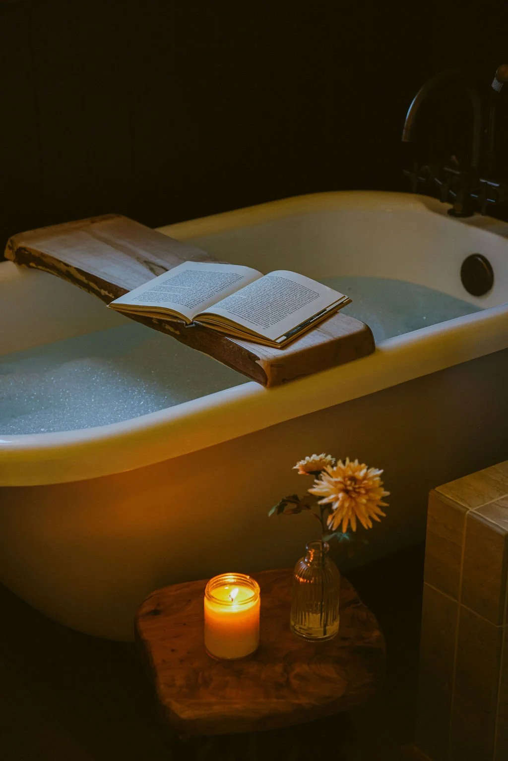 Freestanding soaking tub with a book and a lit candle beside it