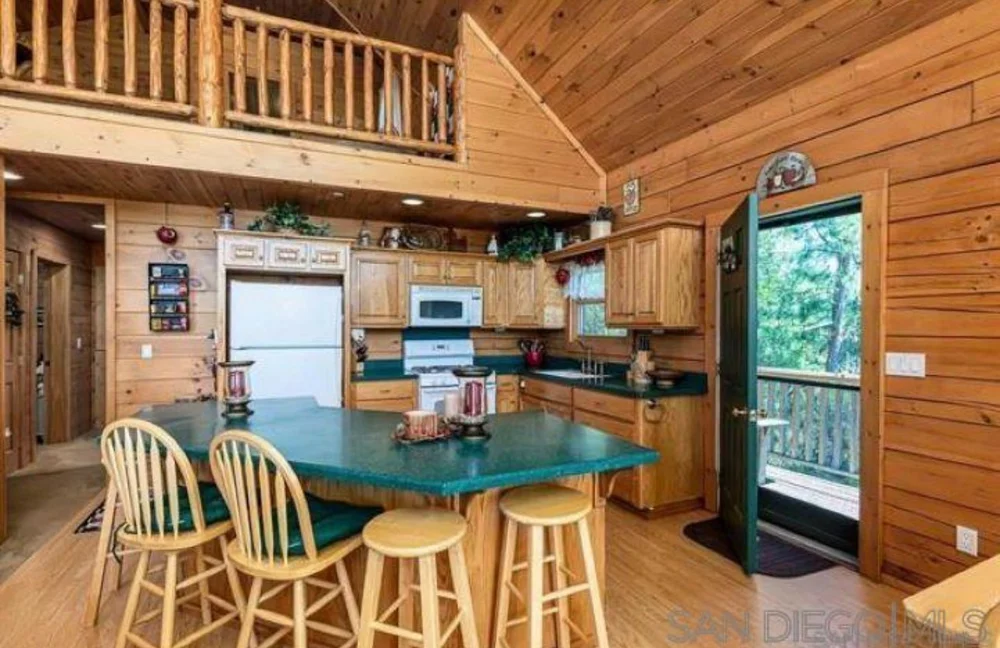 Before: Kitchen with green counters and the loft above at Dark Moon Chalet in Julian