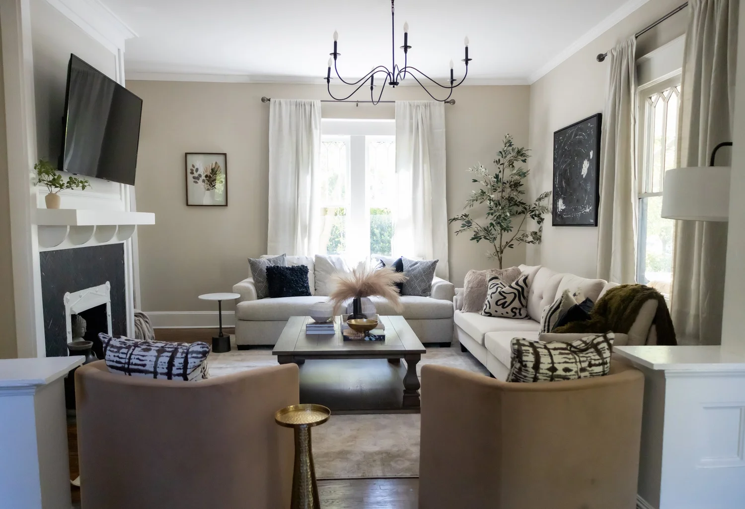 Living room with a fireplace, chandelier and two armchairs at Elmsgate in Birmingham, designed by Salt and Sky Lodging Co.