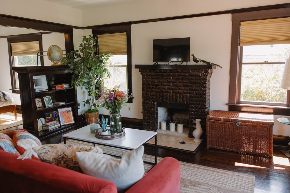 The living room in the upstairs master suite at Palm Parkside, with a brick fireplace, bookshelves and a red sofa
