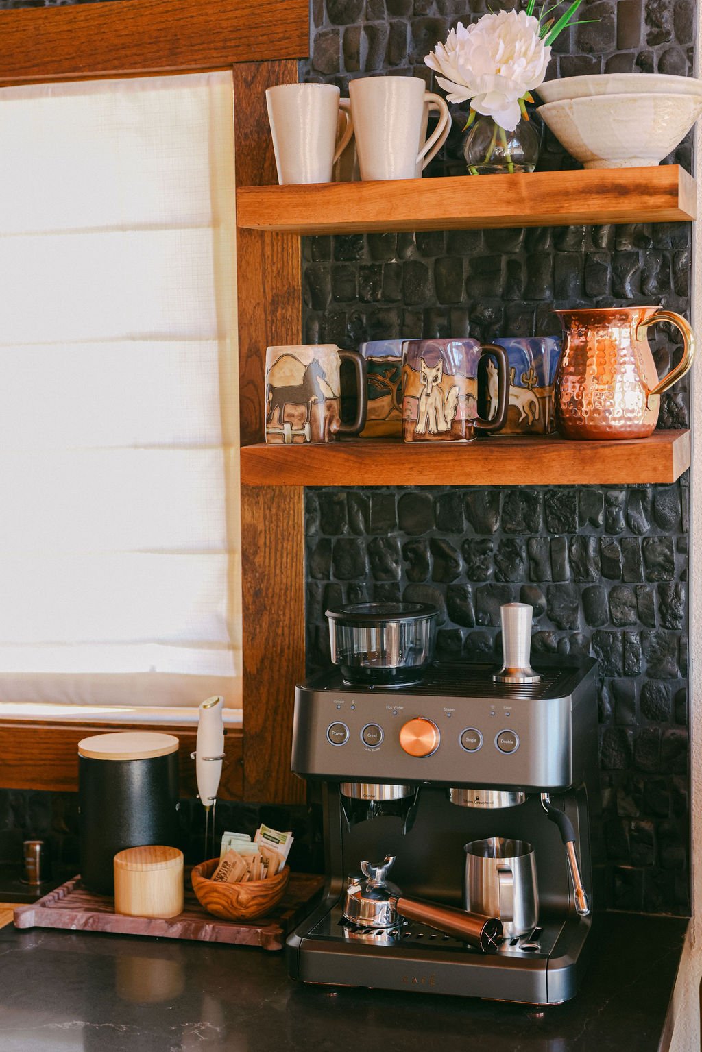 Coffee station with an espresso machine and open shelves on a dark tile wall