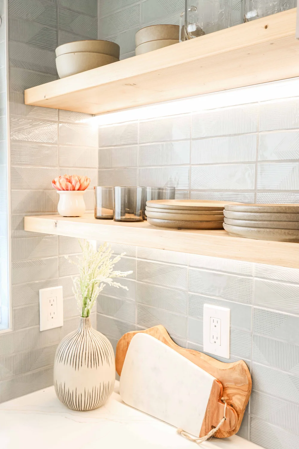 Floating wood shelves with under shelf lighting on blue tile at Clementine B in Oceanside, designed by Salt and Sky Lodging Co.