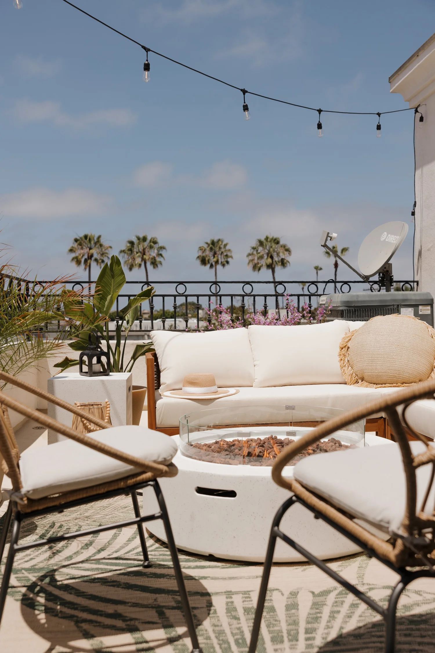 Balcony with a fire table, string lights and palm tree views at Coastal Palm in Pacific Beach, designed by Salt and Sky Lodging Co.