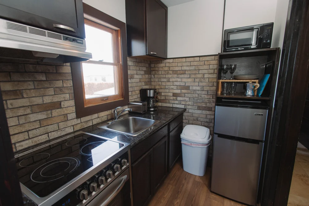 The full kitchen in the upstairs master suite at Palm Parkside, with a stove, sink, fridge and brick backsplash