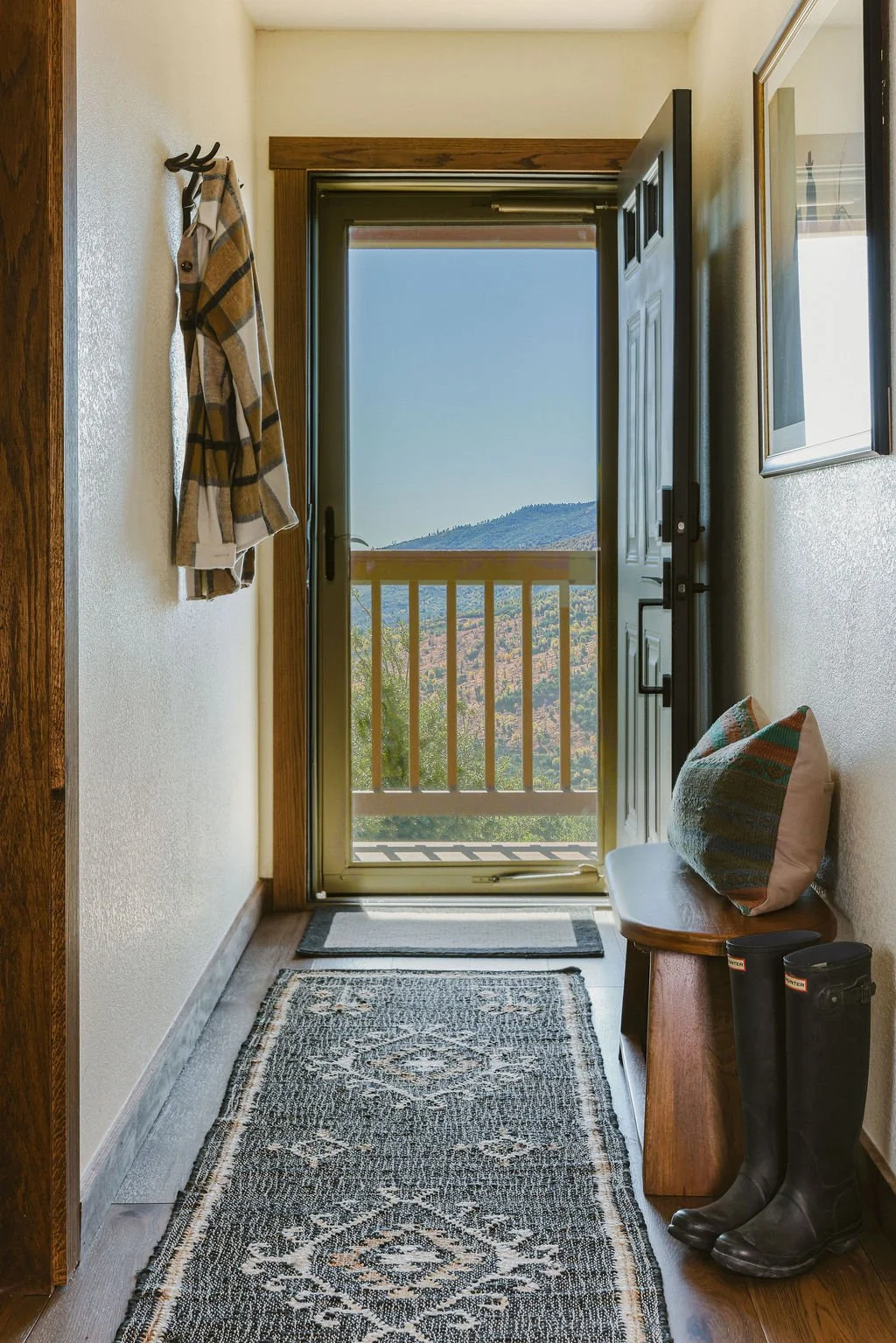 Hallway with a patterned runner leading to a balcony with mountain views