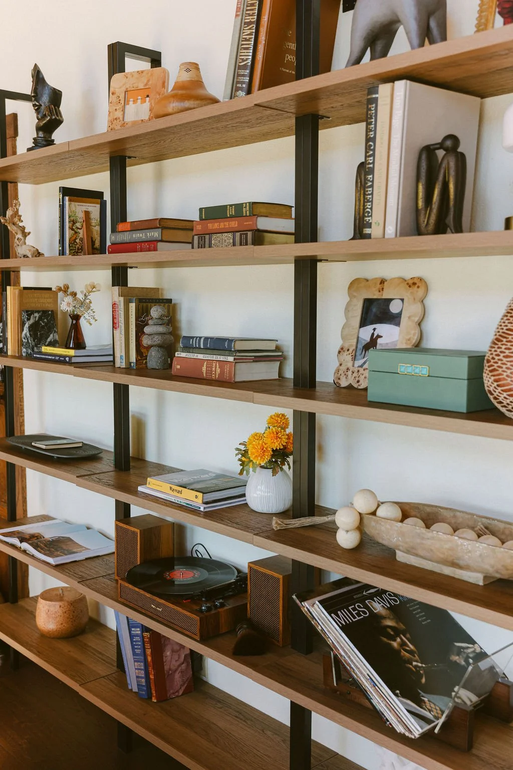 Open wood and metal shelving styled with books, plants and ceramics