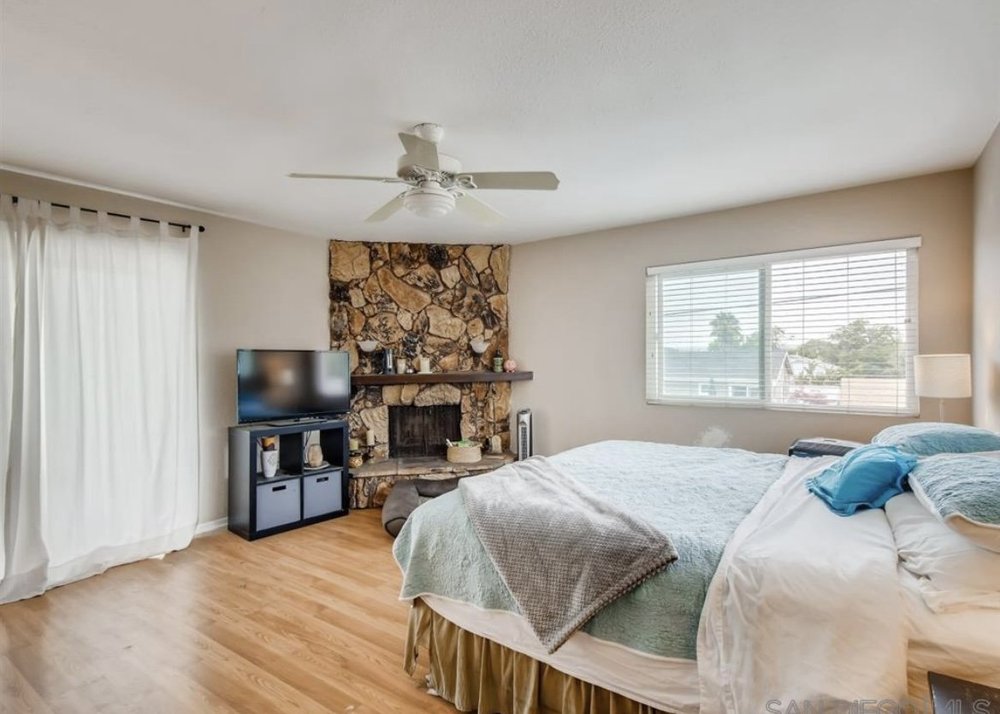 Before: Bedroom with a stone fireplace at OB Surfer's Paradise in Ocean Beach