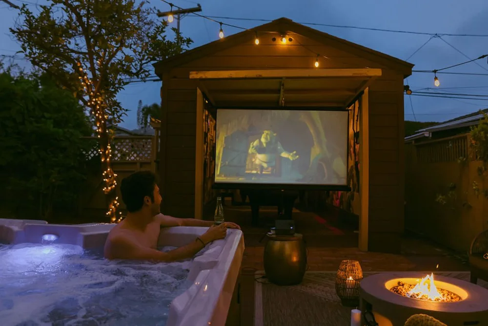 A movie on the outdoor projector seen from the hot tub in the backyard at Palm Parkside at night