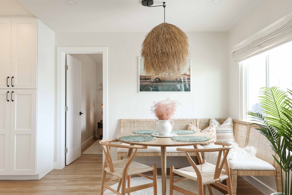 The dining nook with a built-in bench, a round table and a seagrass pendant in Unit One at The Swell, Oceanside