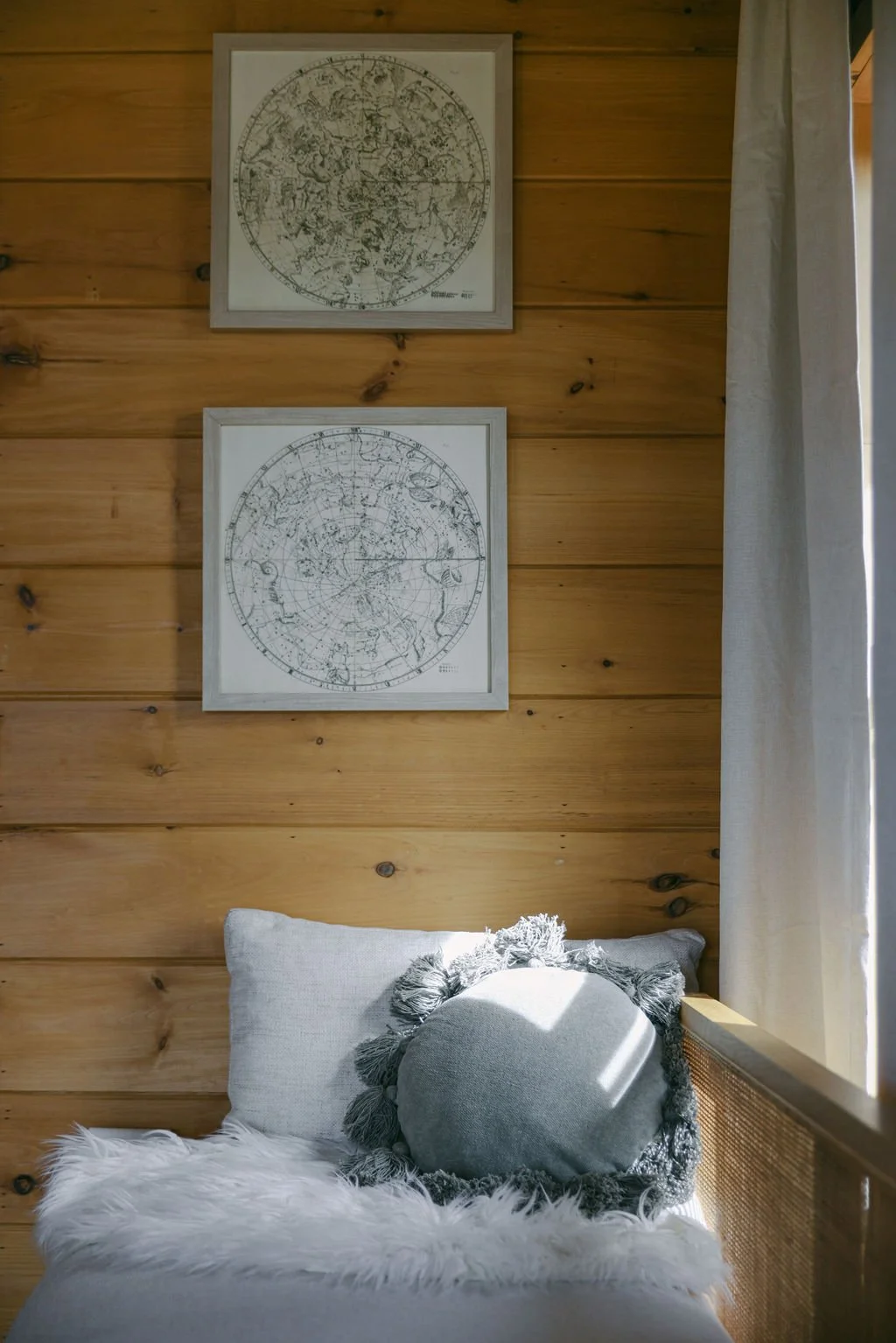 Window seat nook with star map art and a white pillow at Dark Moon Chalet in Julian, designed by Salt and Sky Lodging Co.