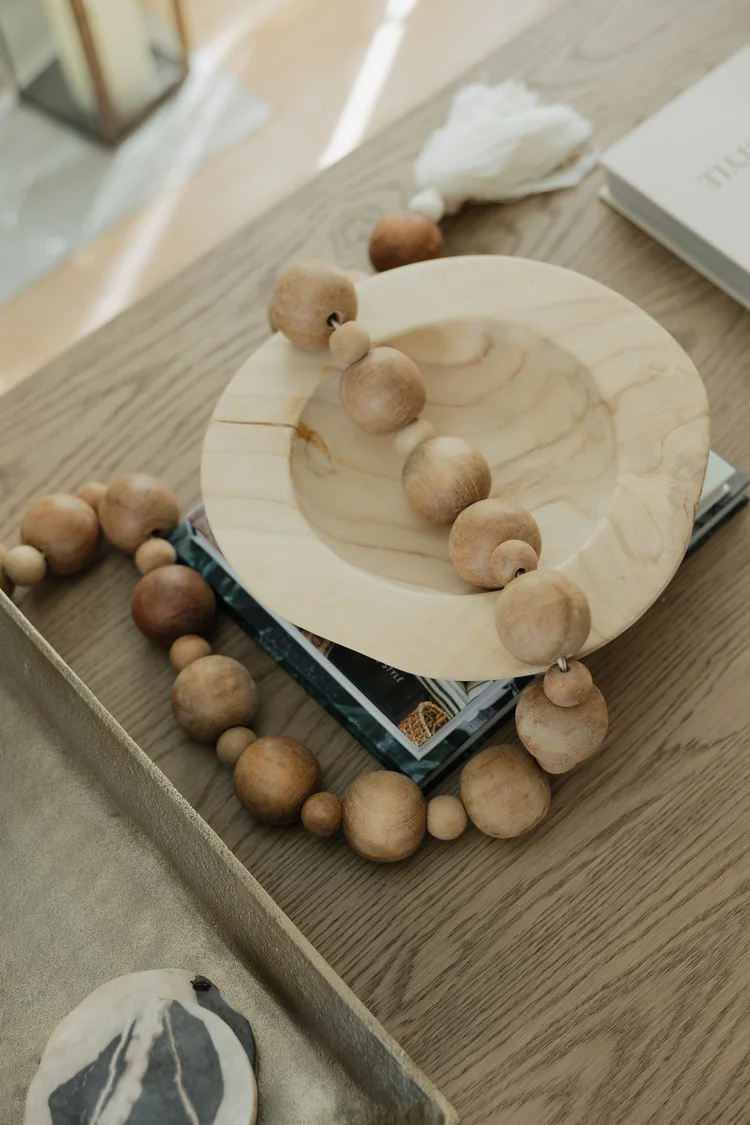 A wood tray with a bead garland and books on the coffee table at Velvet Surf