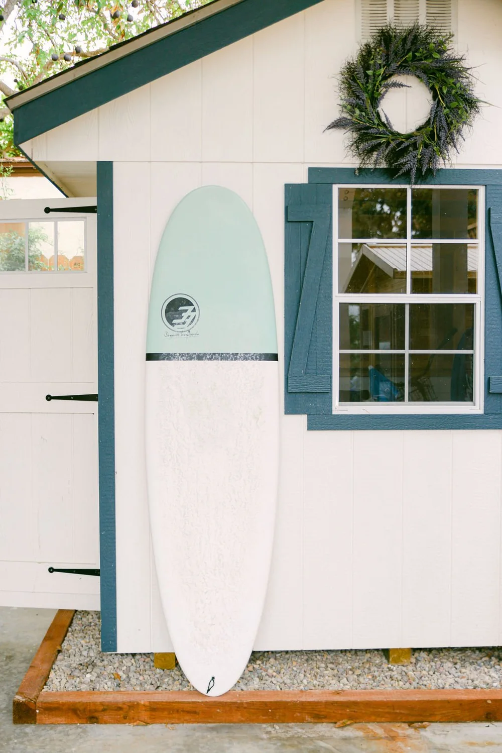 A surfboard leaning against a blue and white beach cottage in Point Loma