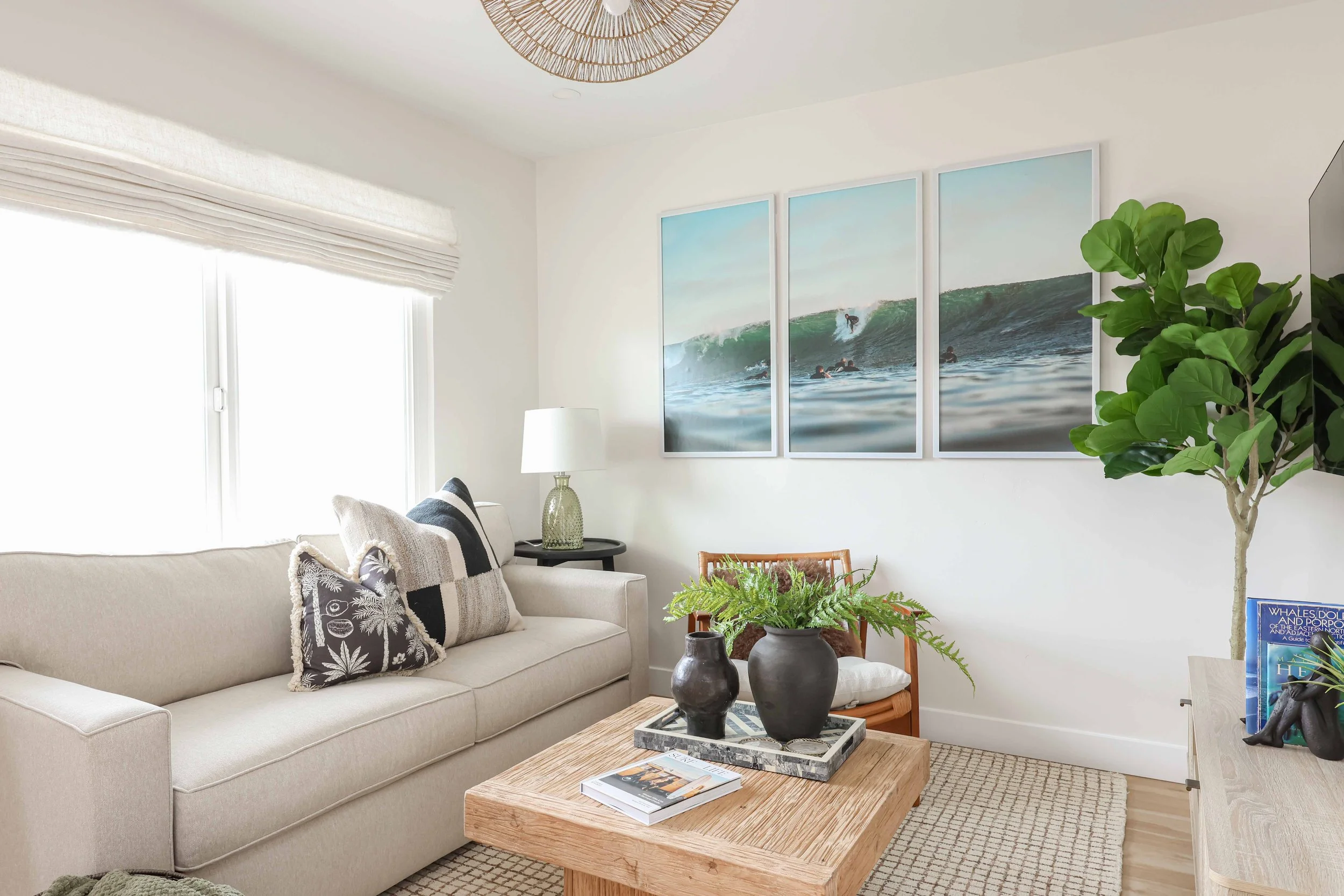 Living room with a cream sofa, surf triptych and fiddle leaf fig at Clementine B in Oceanside, designed by Salt and Sky Lodging Co.