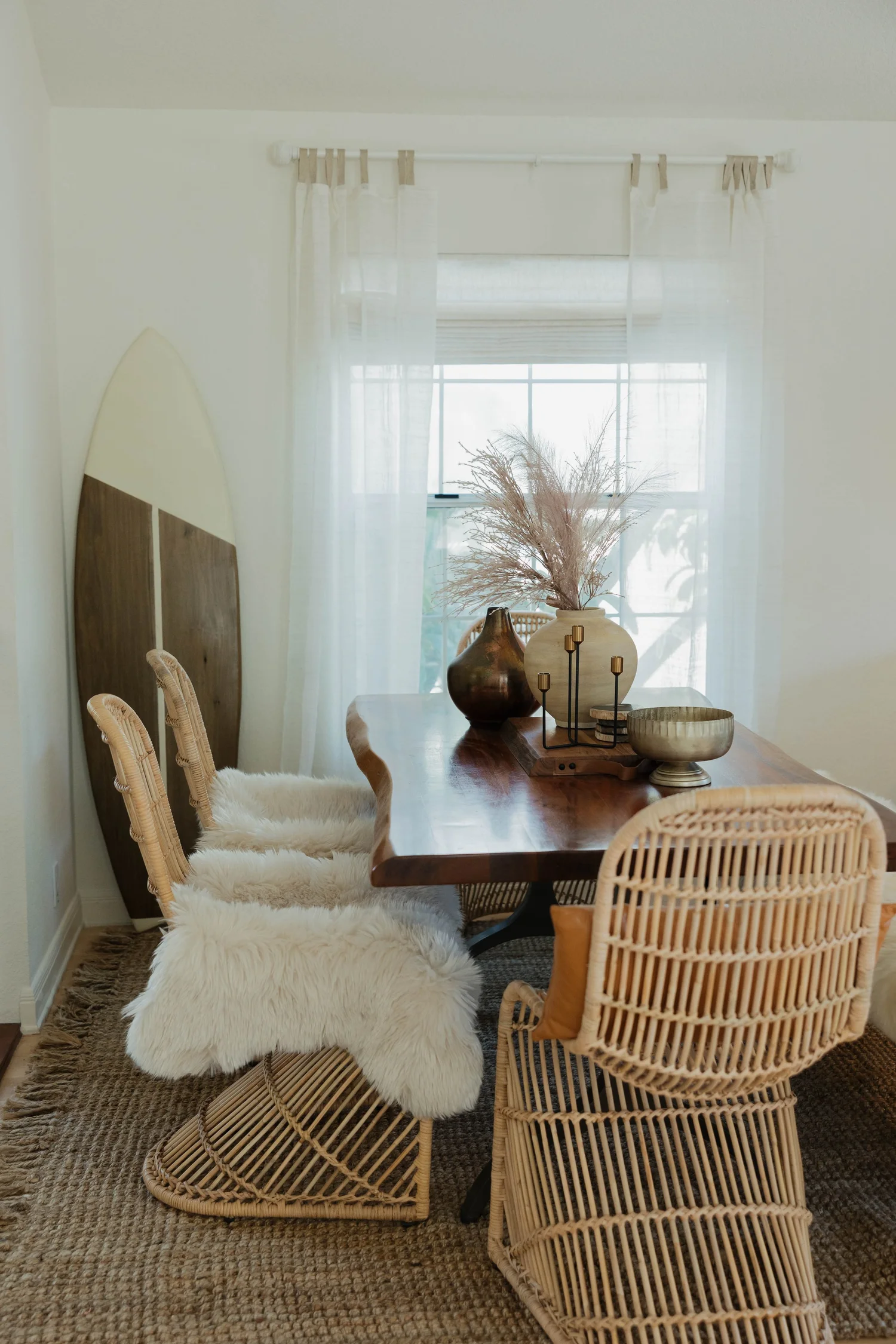 The dining room at Velvet Surf with a wood table, rattan chairs with sheepskins and a surfboard against the wall