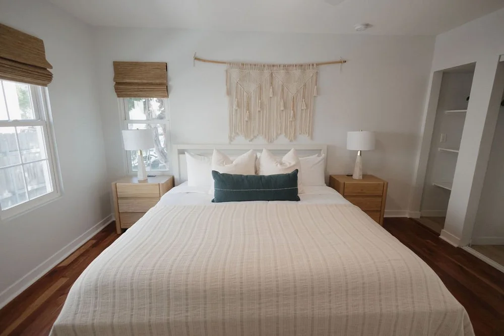 A bedroom in The Villa with a macrame wall hanging and wood floors