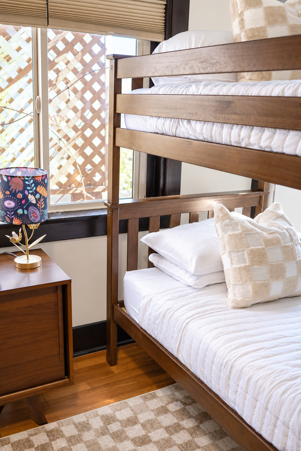 Wood bunk beds with white bedding and checkered pillows in the bunk room at Palm Parkside