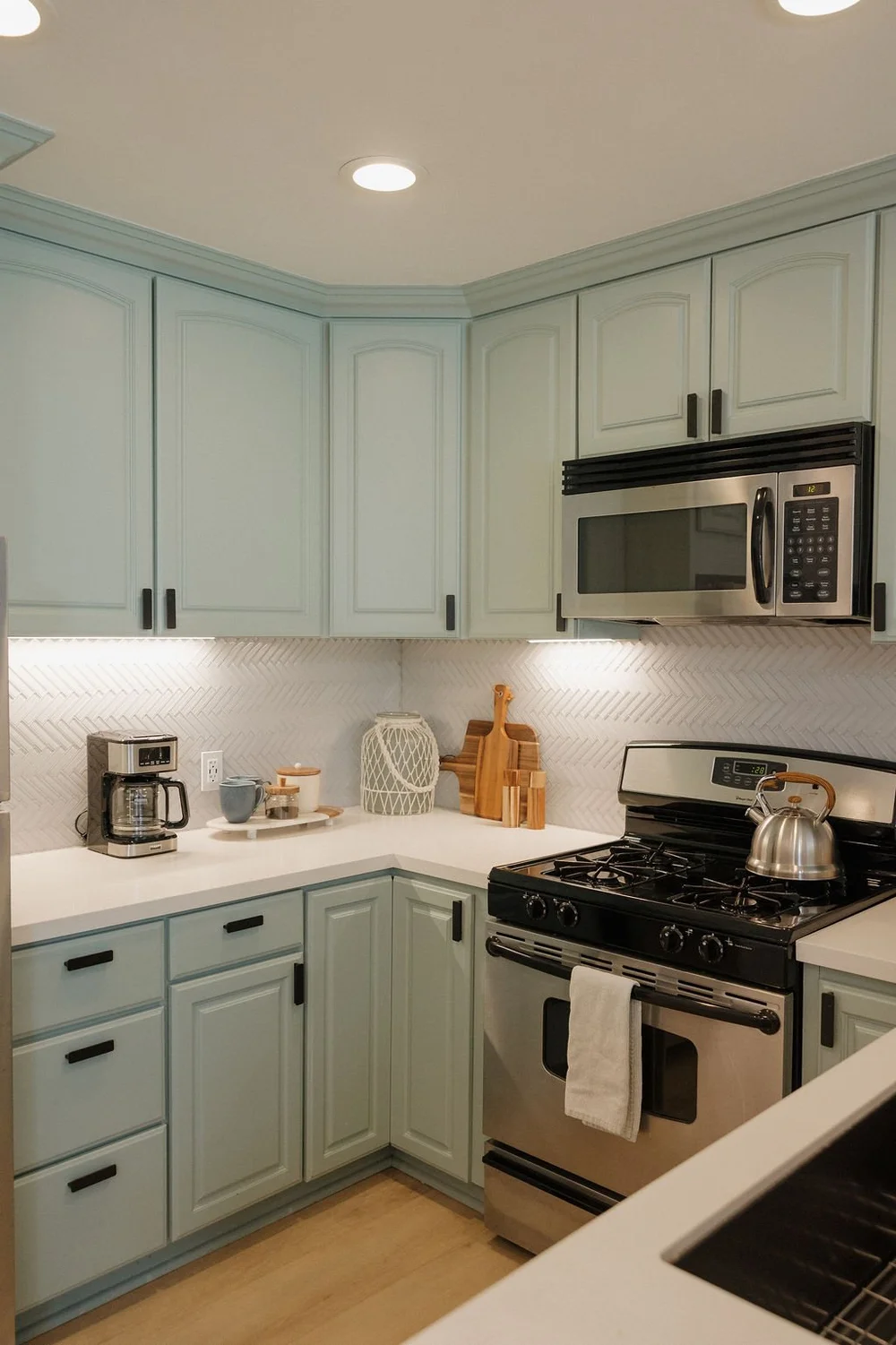 The sage green kitchen with stainless appliances in The East Cove