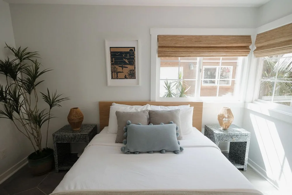 A bright bedroom in The Villa with woven shades and blue pillows