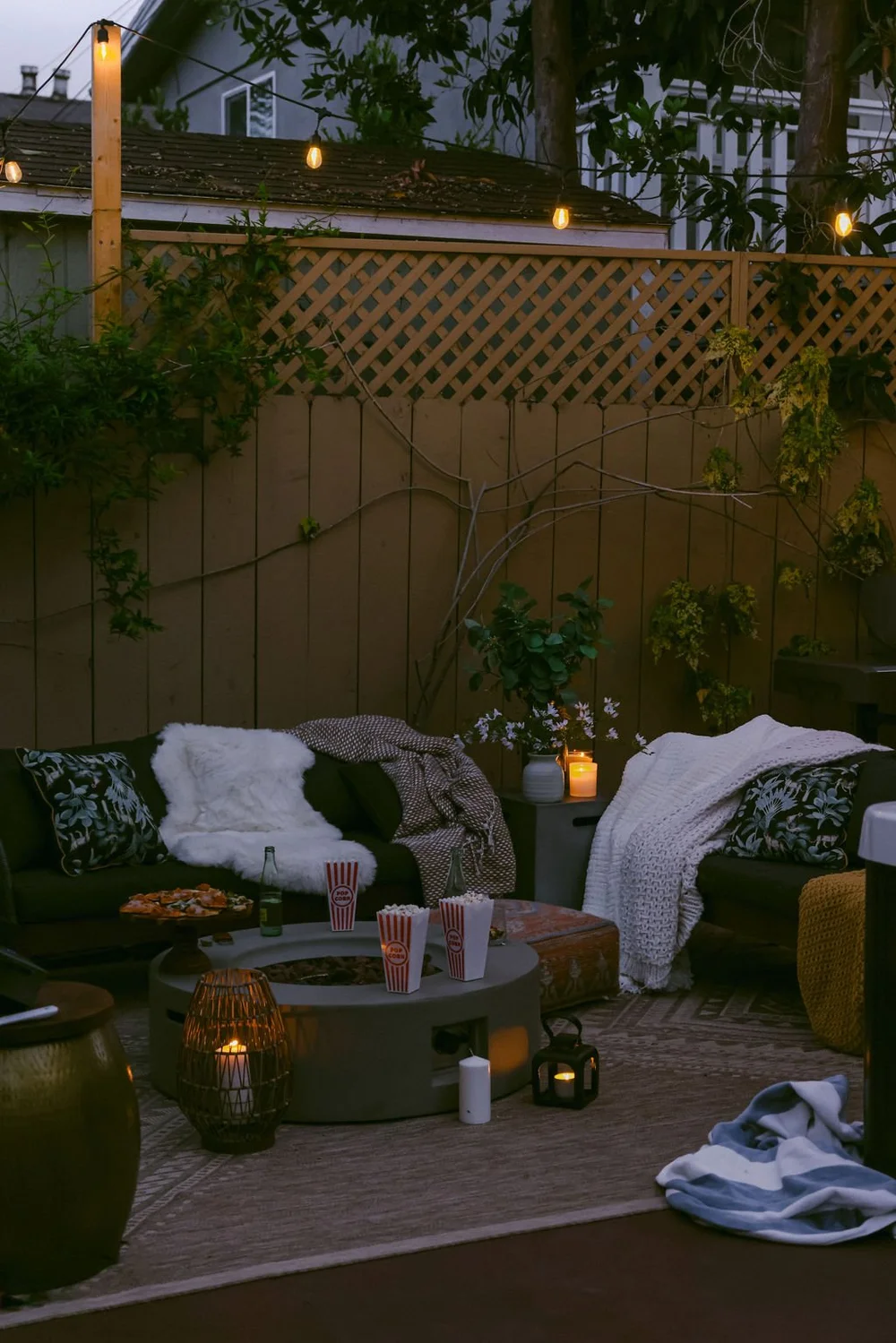 Lanterns, blankets and popcorn around the fire table in the backyard lounge at Palm Parkside in the evening