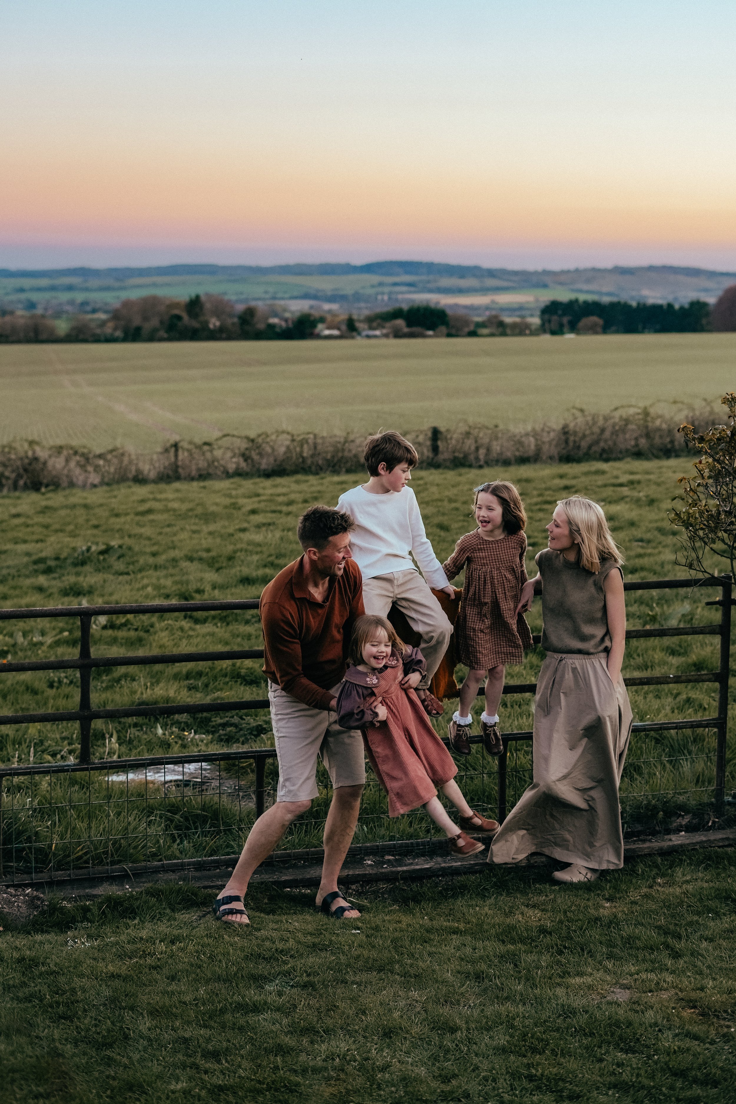 Family of five playing together in front of a sunset during a family photoshoot