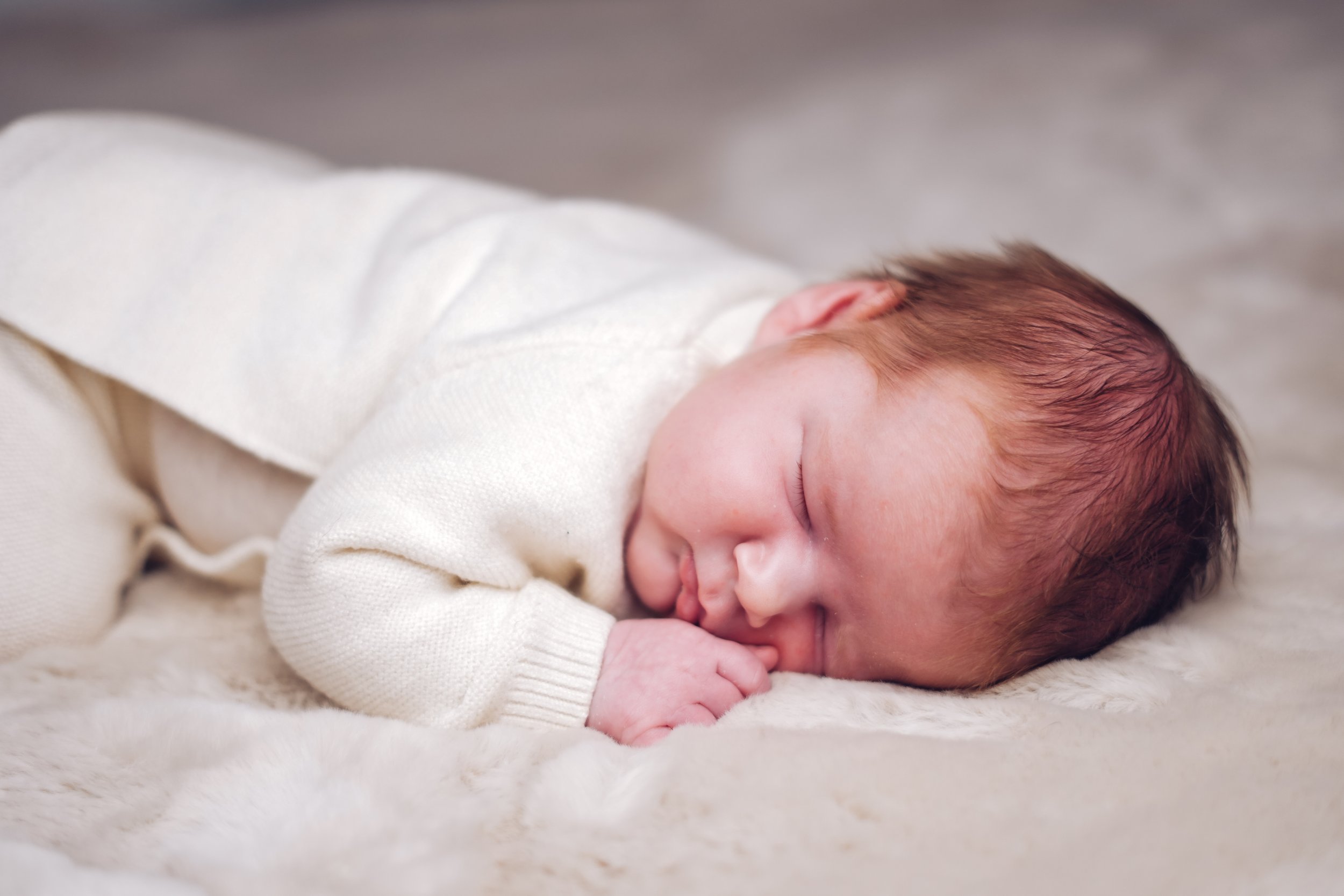 Newborn sleeping on a fluffy blanket during newborn photoshoot in Swansea South Wales