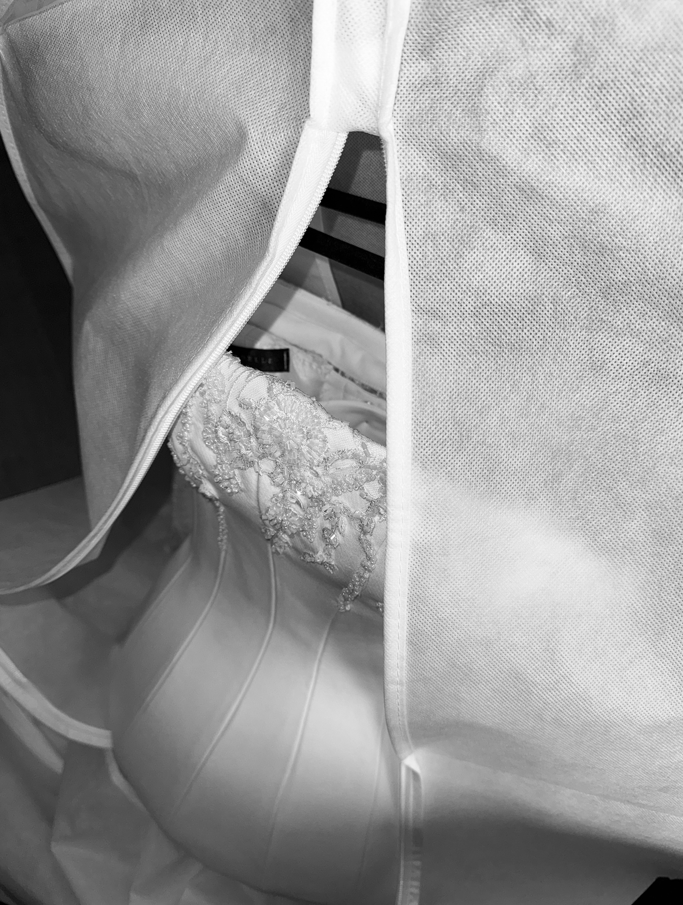 A white wedding veil with lace embroidery resting inside a fabric storage bag.