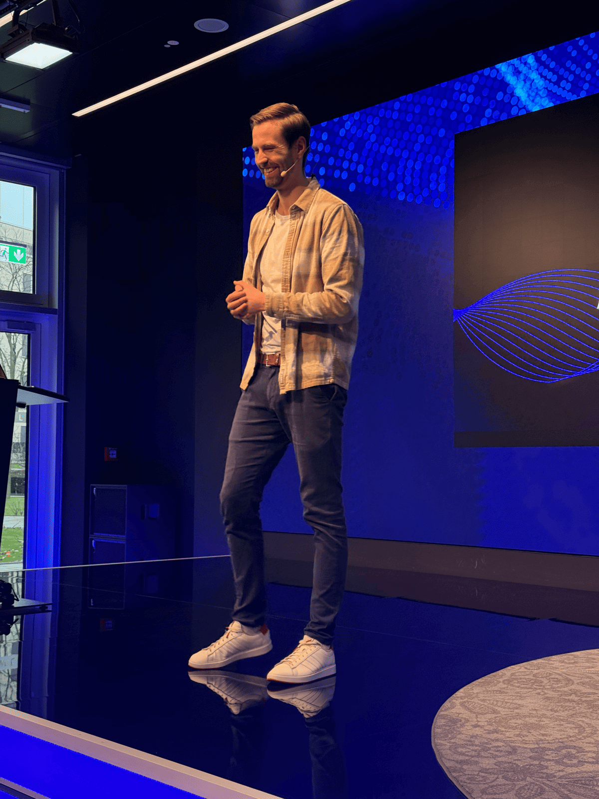 Ein junger Mann steht auf einer Bühne und muss lachen. Das ist wertschätzende Kommunikation