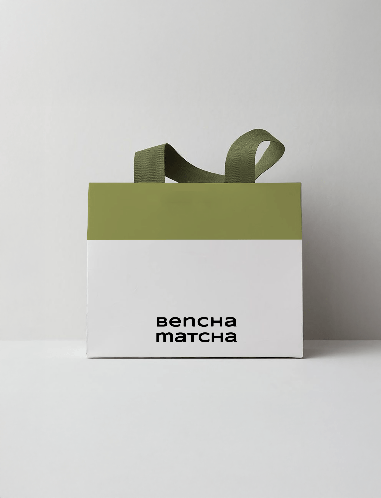 Une boîte blanche avec regardant une étiquette indiquant 'Bencha Matcha' en noir, avec un ruban vert appuyé sur le dessus de la boîte.