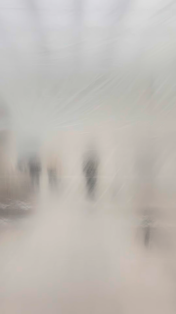 People walking through a foggy or frosted glass surface, creating a blurred and obscured view.