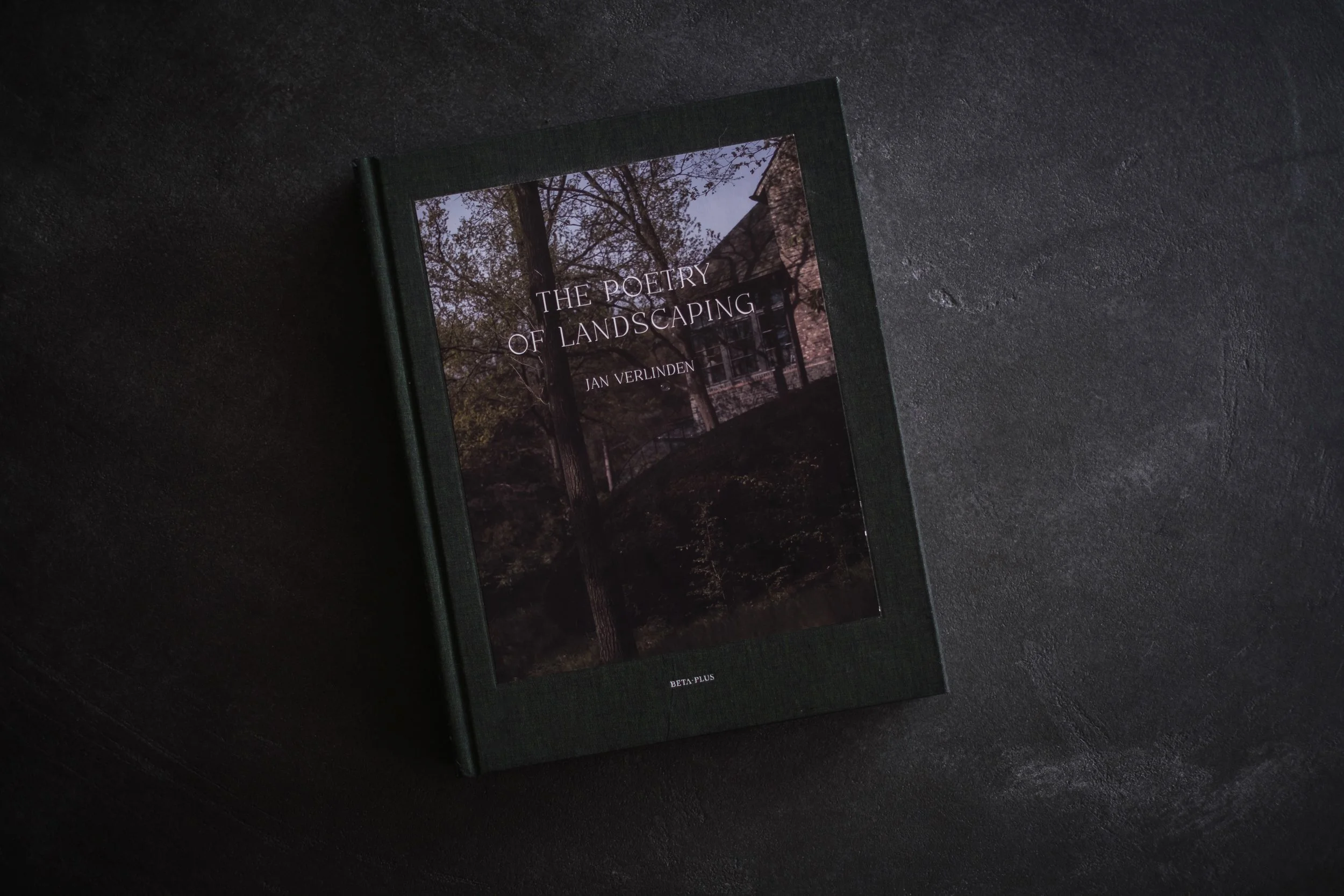 A hardcover book titled 'The Poetry of Landscaping' by Jan Verlinden resting on a dark surface.