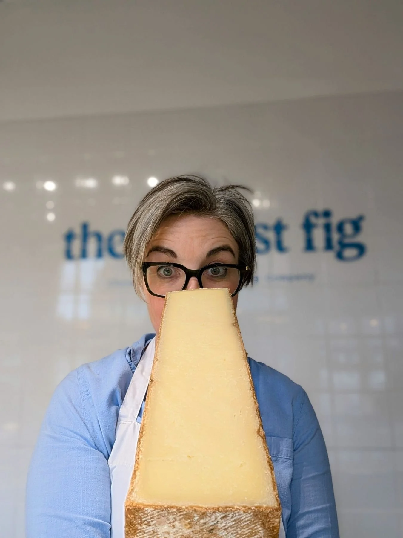 Linda holding a big wedge of cheese in front of her face