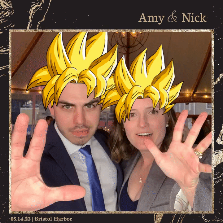A couple at Bristol Harbor wearing super Saiyan hair filters, with the man in a suit and tie, and the woman in a blazer, both holding up their hands as if showing power.
