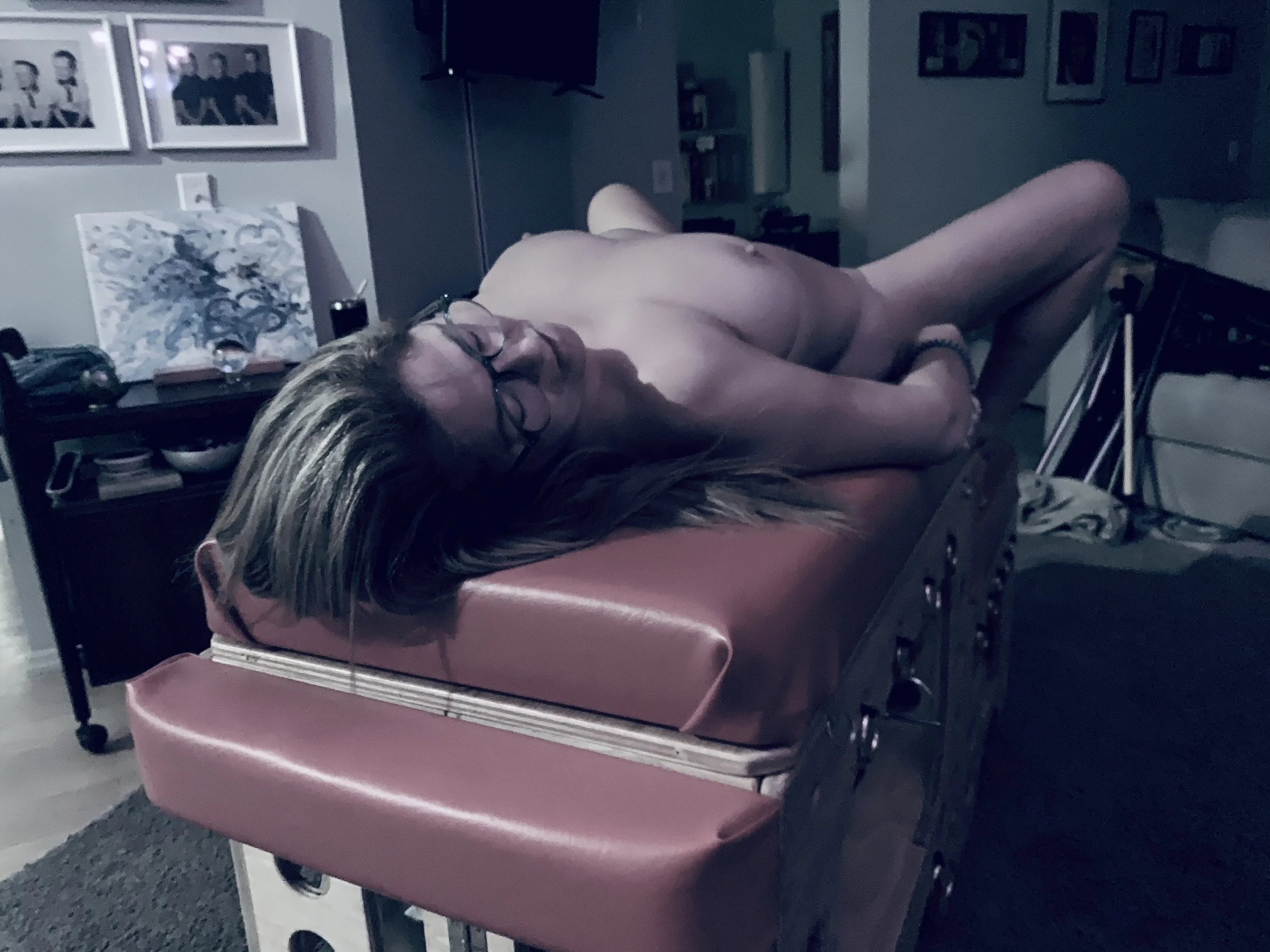 Naked woman lying on a sex bench, ready for a scene.
