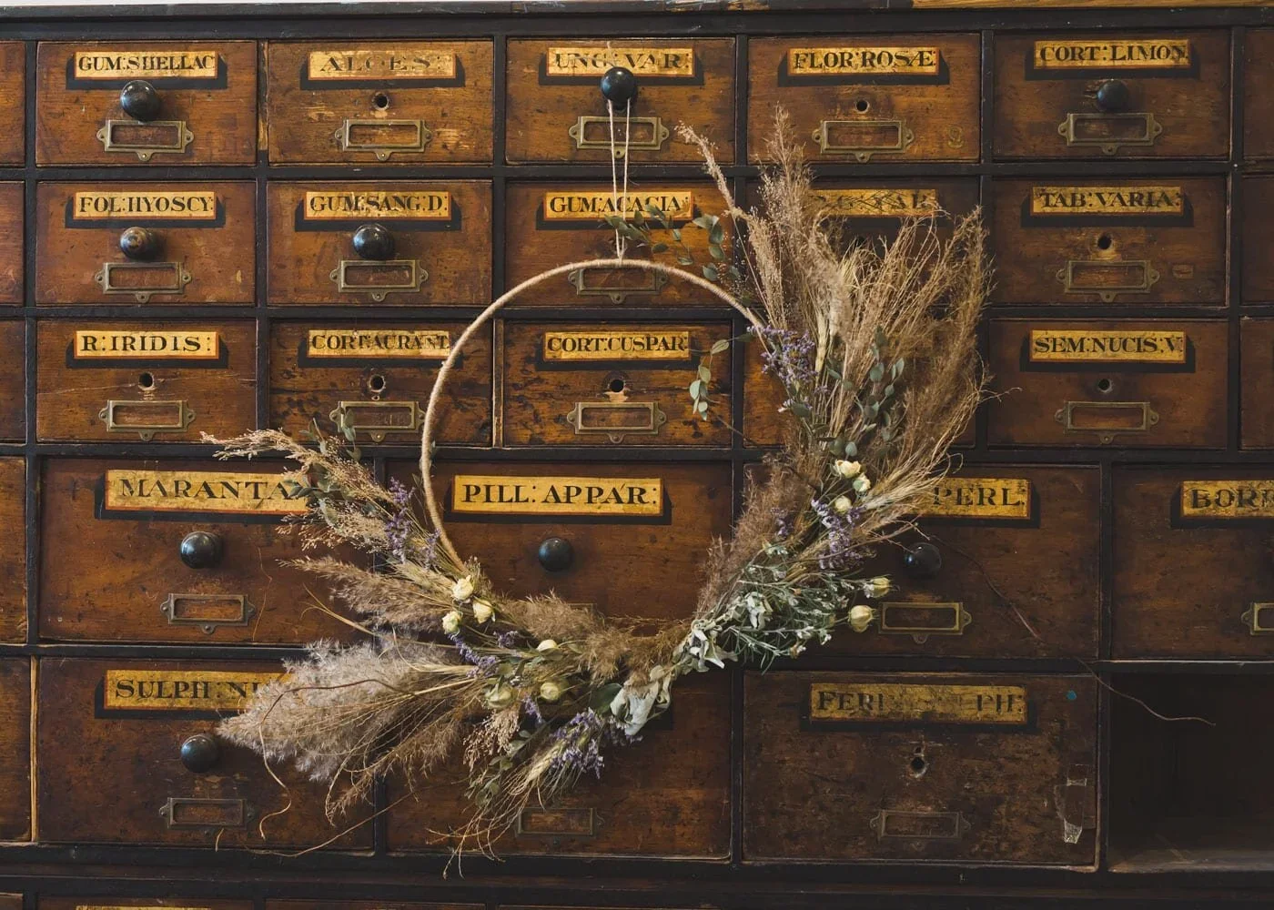  Vintage drawers with wreath made of dried herbs and stems – a quiet nod to craft and memory.