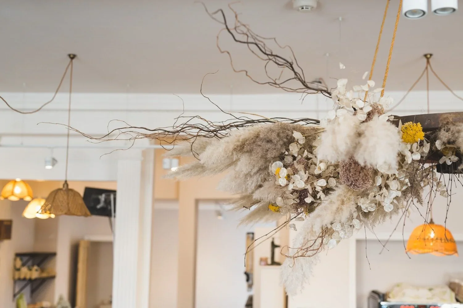 Soft neutral interior with dried branches and flowers styled on a white fireplace – minimal and textural.